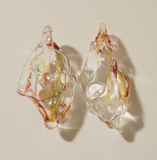 Pair of glass earrings with multicolored swirls on a beige background
