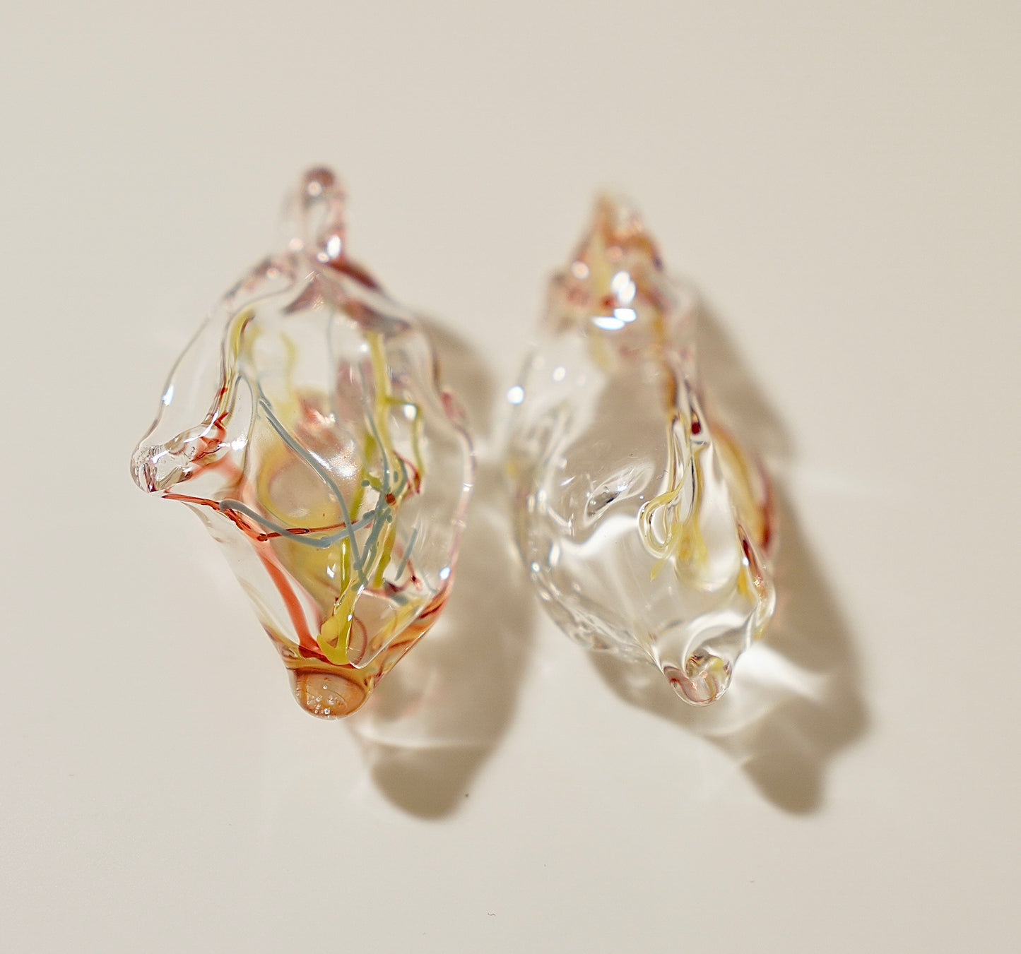 Clear glass earrings with embedded colorful elements on a light background