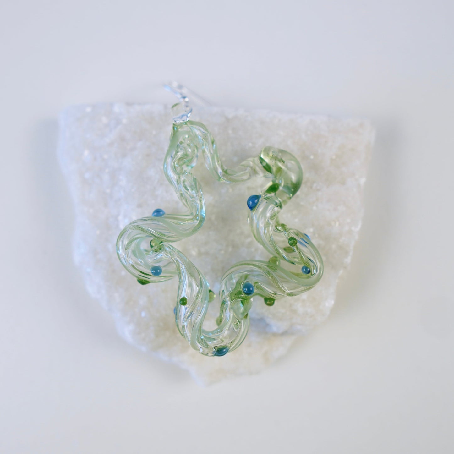 Glass necklace with green and blue swirl design on a white background